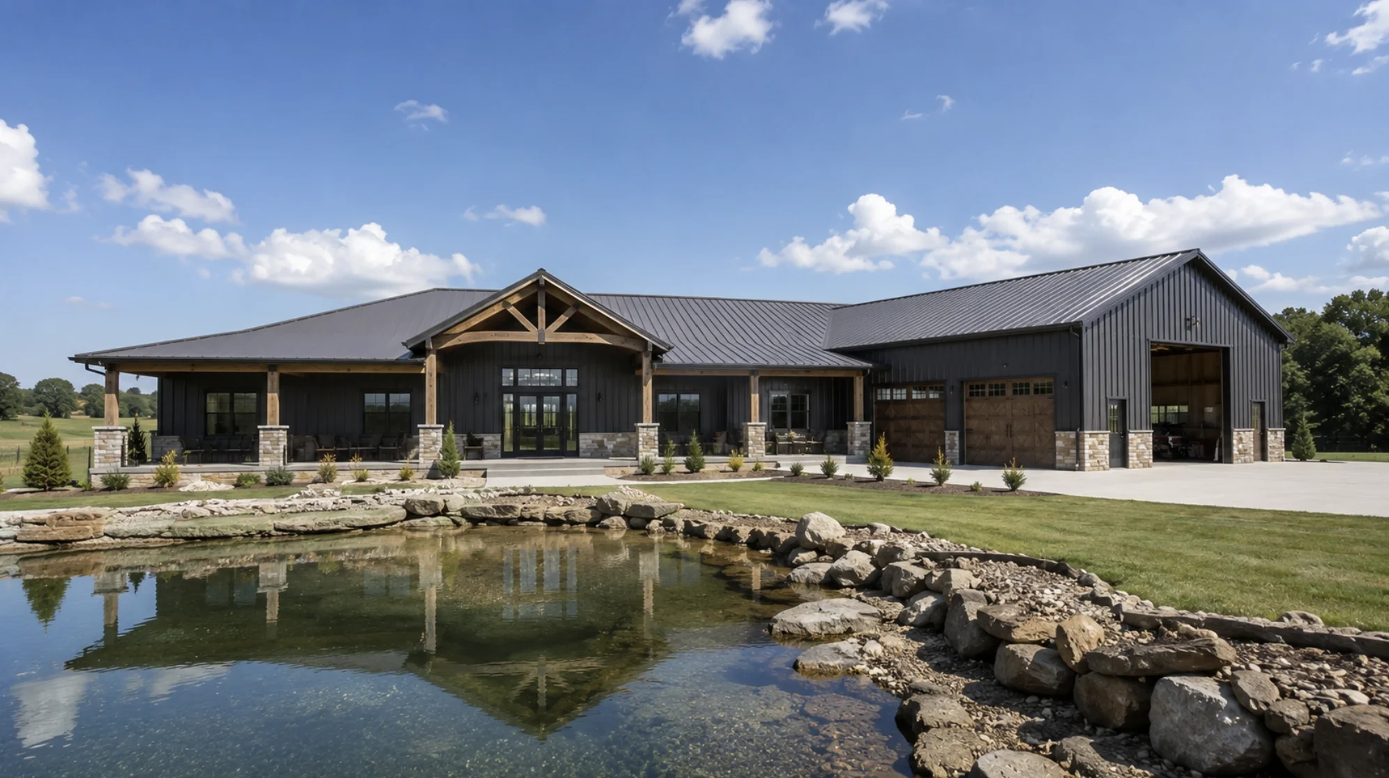 Custom barndominium design in Oklahoma featuring a modern steel-frame home built to fit rural land with a pond, covered porch, and oversized garage.